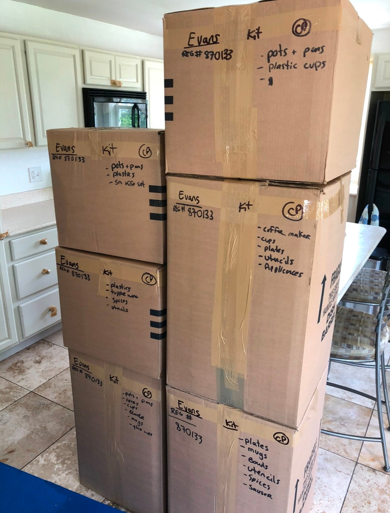 Kitchen contents packed in sealed boxes labeled by room and contents